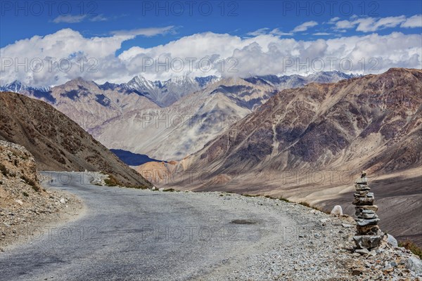 Road in Himalayas near Kardung La pass with stone cairn. Ladakh, India, Asia