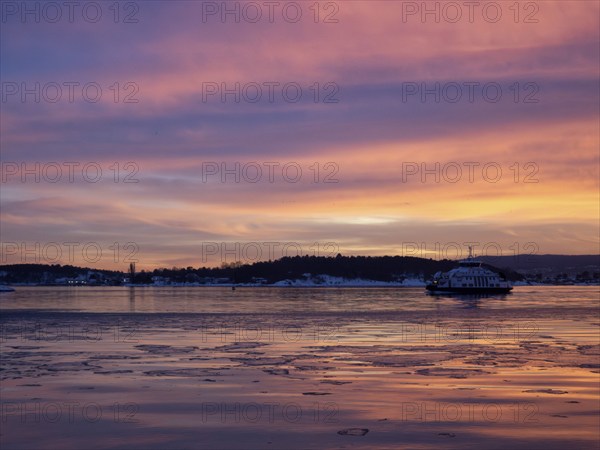 A beautiful sunset over the Oslofjord with a ferry approaching oslo