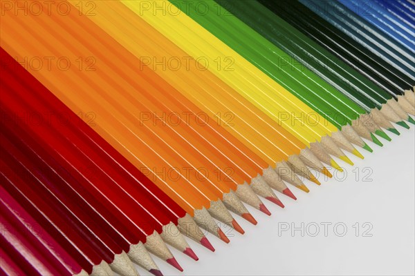 Abstract composition of a set wooden colour pencils against a white background