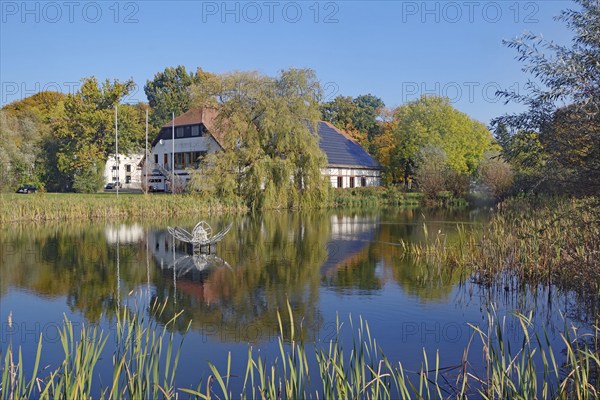 House on the lake with a clear reflection in the water, surrounded by autumnal nature, Fleesensee