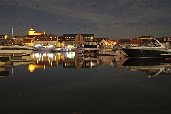 Boats in the harbour at night, illuminated cityscape reflected, Waren, Müritz,