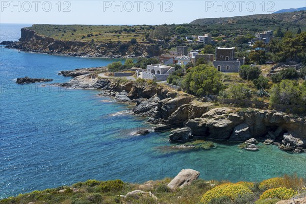 Coastal landscape with rocky shores, clear blue water and picturesque houses under a clear sky,