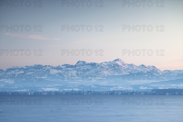 Snow-covered mountains in the Alpstein with Säntis in the background of a lake at dusk with wintry