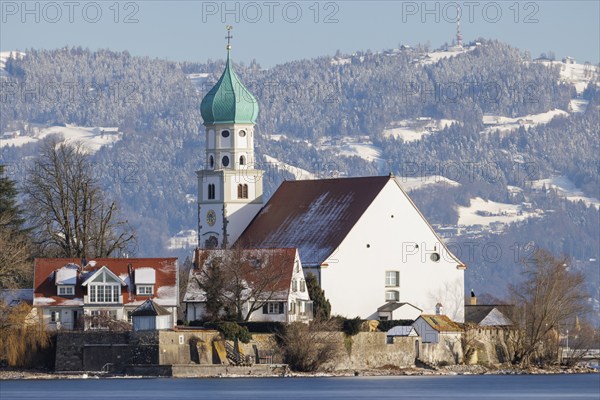 St George's Church with green tower in front of snow-covered Pfänder, surrounded by village houses,