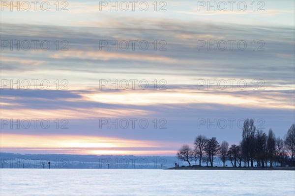 A peaceful sunset over a lake with silhouetted trees and a colourful evening sky, harbour,