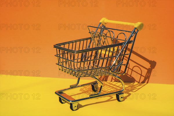 Empty shopping trolley cart on colorful orange yellow background. Copy space for your text. Online