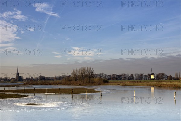 Frozen river foreland from the river Maas near the Dutch village Batenburg with the church tower