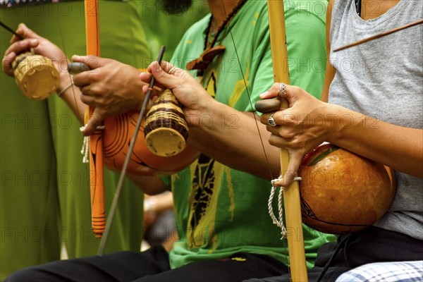 Musicians playing an Afro Brazilian percussion musical instrument called a berimbau during a