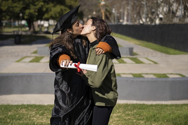 Woman recent graduated, dressed in cap and gown, showing off his degree celebrating with her