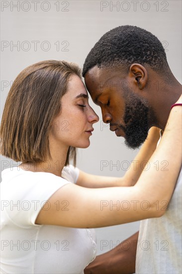 Vertical side view of multi-ethnic lovers about to kiss facing each other with eyes closed