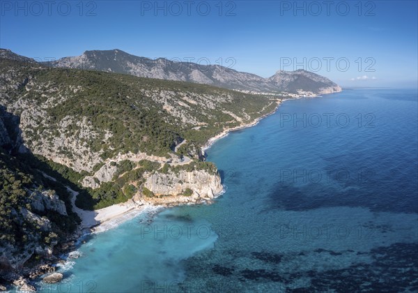 Aerial view of the rugged mountainous coast near Cala Gonone with turqouise water and small white