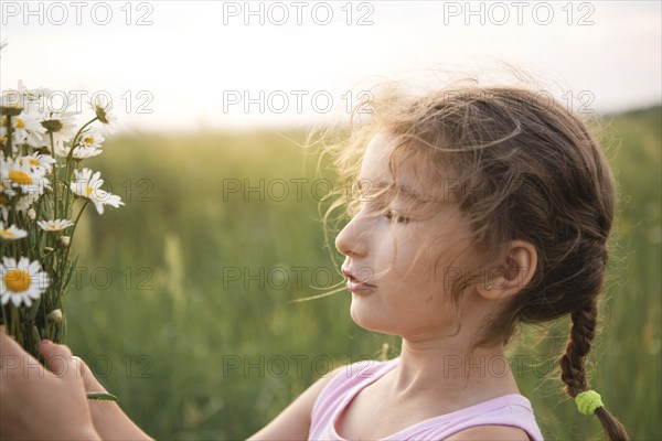 Portrait cute child girl with a bouquet of chamomile in summer on a green natural background. Happy