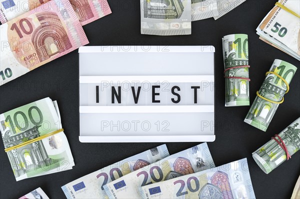 Lightbox board with word INVEST in black letters around euro banknotes. Money, Business, finance,