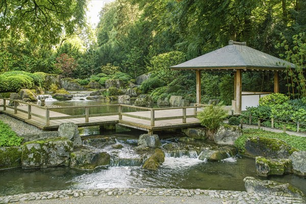 Wooden gazebo and a small waterfall in the Japanese garden in the botanical garden in Augsburg.