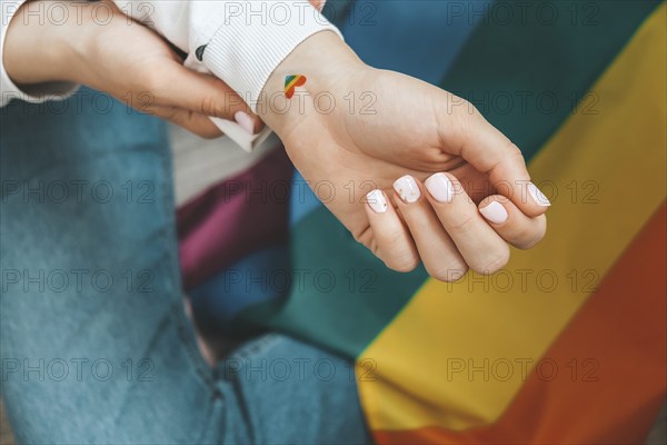 Closeup of young caucasian millennial hippie woman with a rainbow flag in heart shape painted in