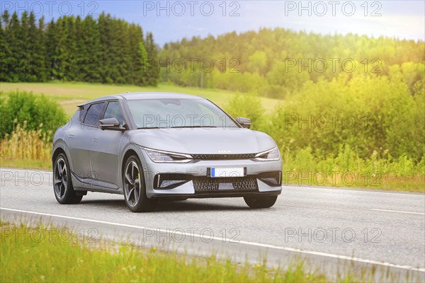 Silver Kia EV6 battery electric car at speed on highway in golden summer sunlight