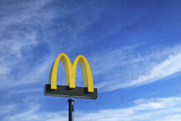 McDonald's logo against blue sky and white fair weather clouds at McDonald's restaurant in Salo,