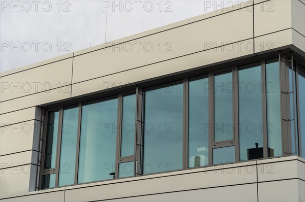 Modern office building with large windows that reflect the blue sky and emphasise the modern