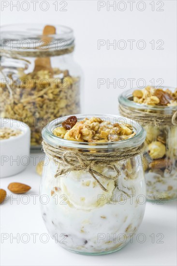 Healthy breakfast. Oatmeal Granola with greek yogurt and nuts banana muesli in jars on light