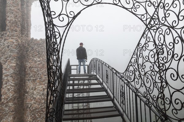 Rye, Colorado, A main stands on an open stairway, high above the ground, at Bishop Castle on a