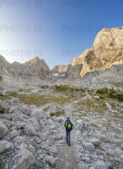 Mountaineer on a hiking trail, rocky mountain peaks Blaueisspitze and Hochkalter at sunrise,