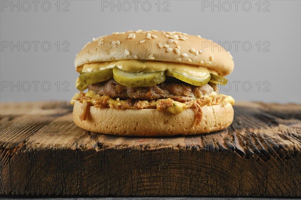 Beef burger with pickled cucumber and onion crumbs front view