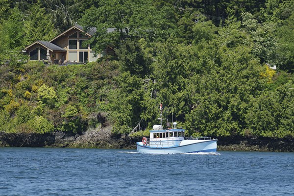 Small fishing boat in front of forest and single house, good weather, Ucluelet, Pacific Rim