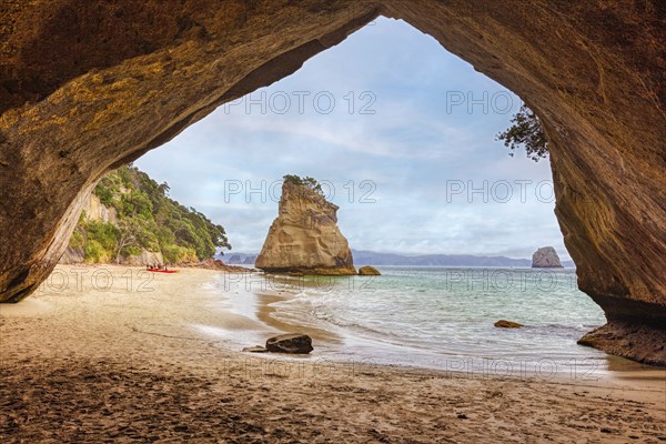 View from a cave opening onto a sandy beach and a solitary rocky outcrop in the sea, Cathedral
