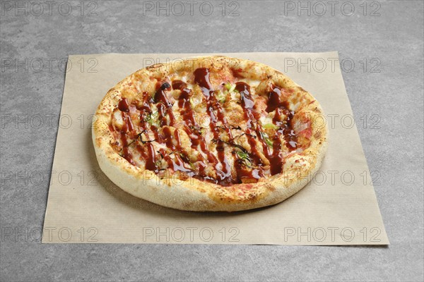 Barbecue pizza with bacon and spring onion on parchment paper