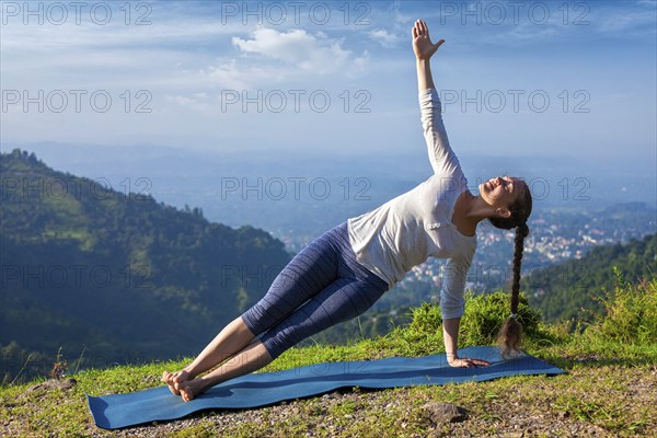 Yoga outdoors, beautiful sporty fit woman doing yoga asana Vasisthasana, side plank pose in