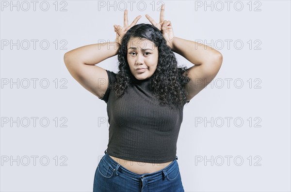 Funny girl making horns gesture with their fingers, gesture of betrayal. Funny young woman making