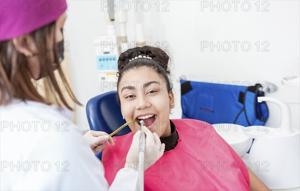 Stomatologist woman with drill cleaning patient girl mouth. Stomatologist drilling and cleaning a
