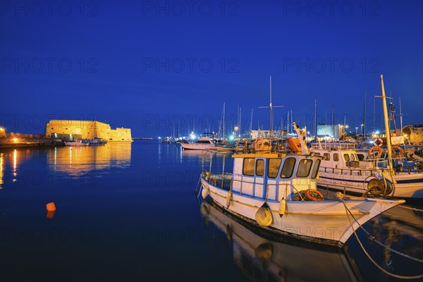 Venetian Fort castle in Heraklion and moored Greek fishing boats in port, Crete Island, Greece in