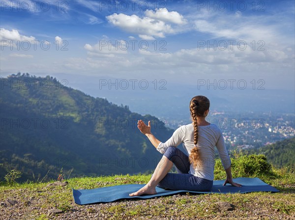 Hatha yoga outdoors, sporty fit woman doing yoga asana Parivrtta Marichyasana (or ardha