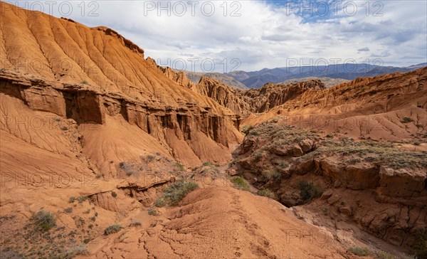 Eroded mountain landscape with sandstone cliffs, canyon with red and orange rock formations,