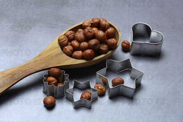 Wooden ladle with hazelnuts, cookie cutters, baking ingredient