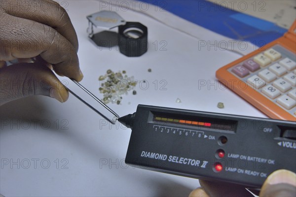 Diamond dealer inspecting a diamond for its authenticity, Koidu, Koidu-Sefadu, Kono District,