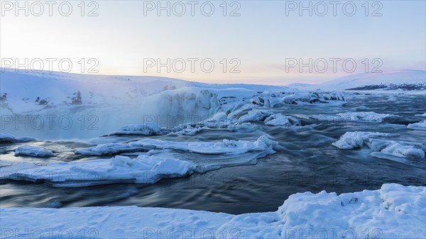 Icefall at the edge of the Godafoss waterfall at dawn, snow-covered landscape, Northern Iceland