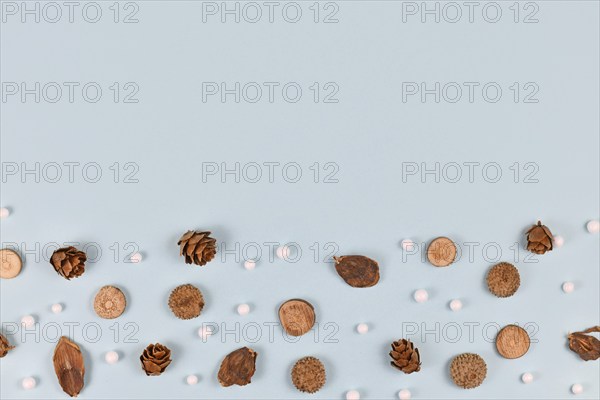 Seasonal hernlock cones, acorn hats, stick slices and white snowball ornaments at bottom of light