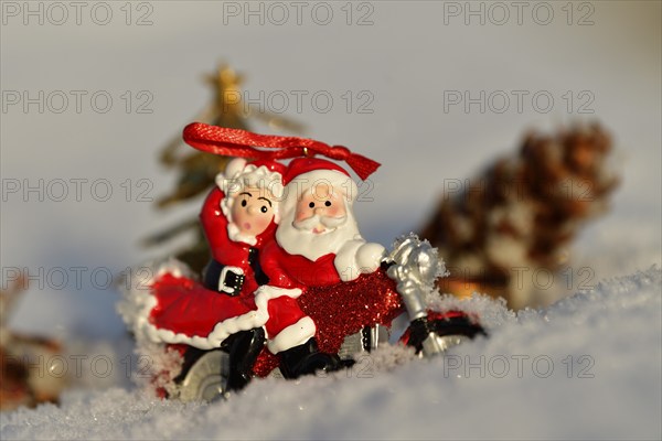 Christmas decorations, Santa and Mrs Claus riding through the snow on a motorbike