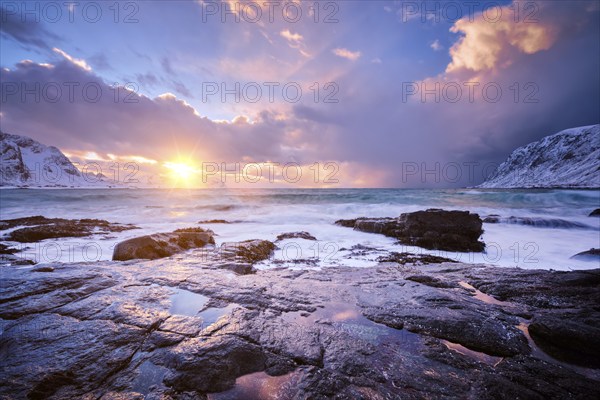 Beach of Norwegian sea on rocky coast in fjord on sunset in winter. Vareid beach, Lofoten islands,