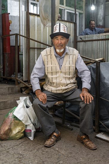 Man with traditional clothes shopping, market stall, Uzgen Bazaar, Ösgön, Osh region, Kyrgyzstan,