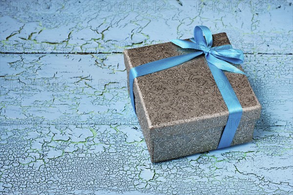 Gift birthday Christmas present concept, silver gift box with blue ribbon on blue painted wooden