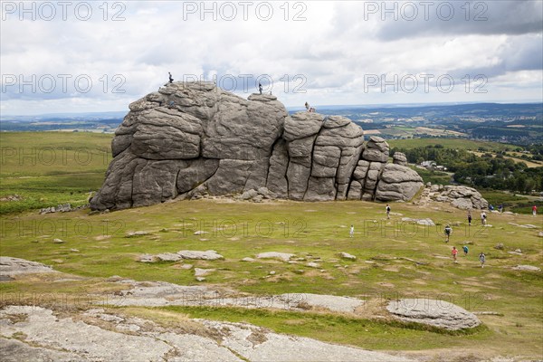 People scrambling on the granite tor of Haytor, Dartmoor national park, Devon, England, UK