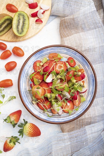 Vegetarian fruits and vegetables salad of strawberry, kiwi, tomatoes, microgreen sprouts on white