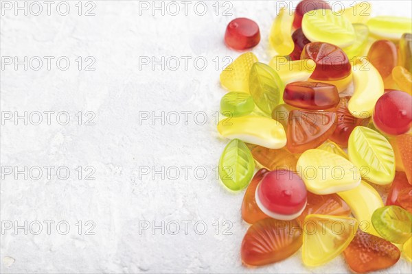 Various fruit jelly candies on gray concrete background. side view, copy space