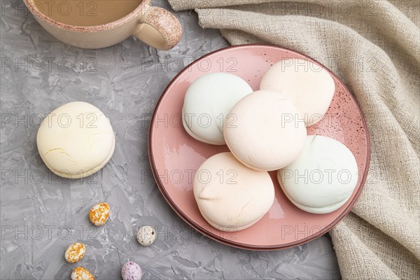 Colored zephyr or marshmallow with cup of coffee and dragees on a gray concrete background and