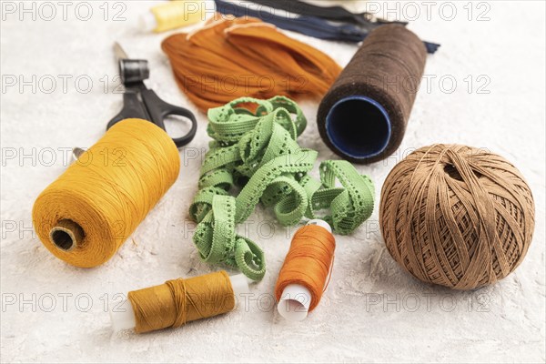 Sewing accessories: scissors, thread, thimbles, braid on gray concrete background. Side view, close