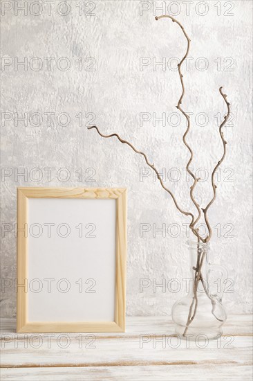 White wooden frame mockup with dried wine branch in glass on gray concrete background. Blank,