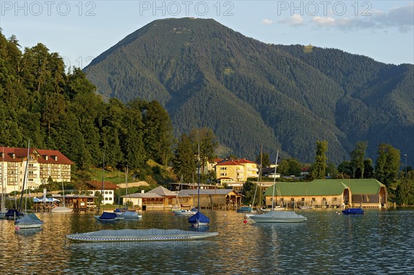 Tegernsee with sailing boats and boat huts, warm evening light, town Tegernsee, mountain Wallberg,